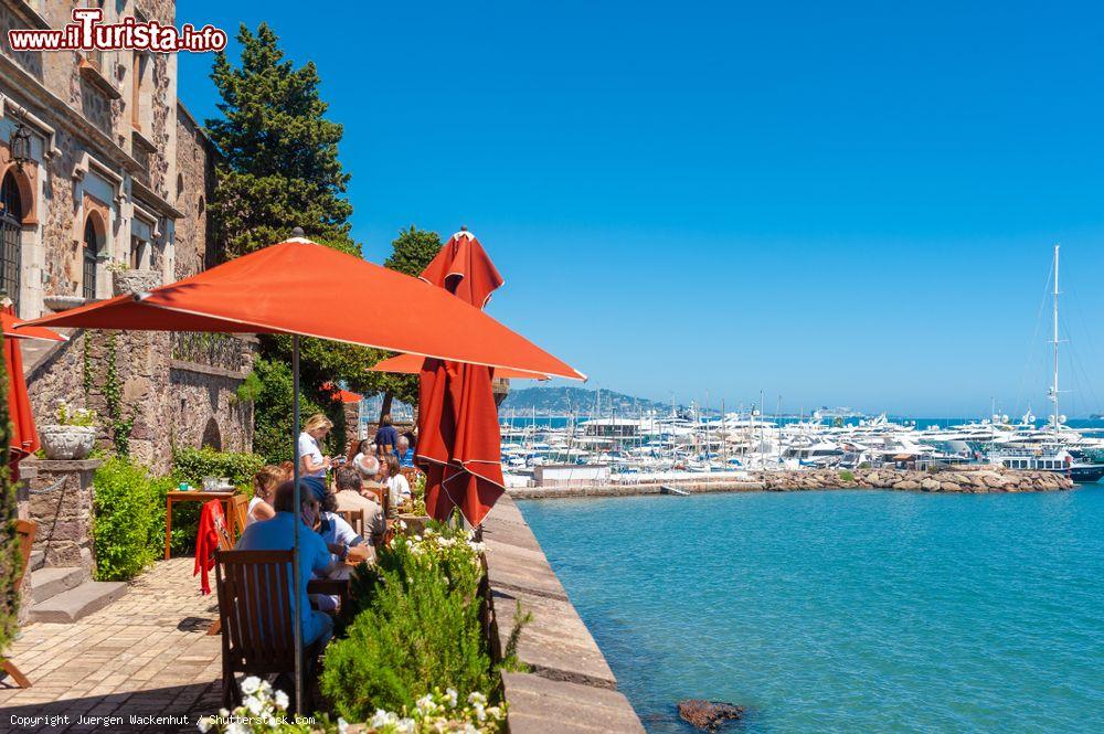 Immagine Un ristorante di Mandelieu-la-Napoule di fronte al porto con turisti seduti ai tavoli all'aperto (Francia) - © Juergen Wackenhut / Shutterstock.com