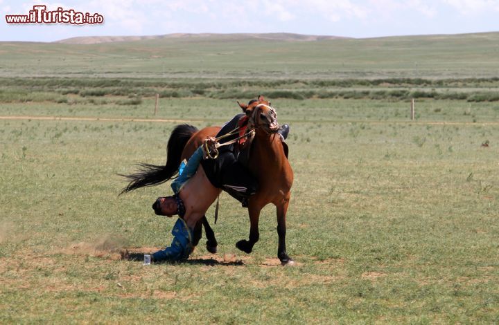Immagine Un tipico divertimento mongolo nelle steppe vicino a Hohhot, Cina. Un giovane uomo intento a cavalcare un cavallo cerca di raccogliere una banconota da terra - © Katoosha / Shutterstock.com