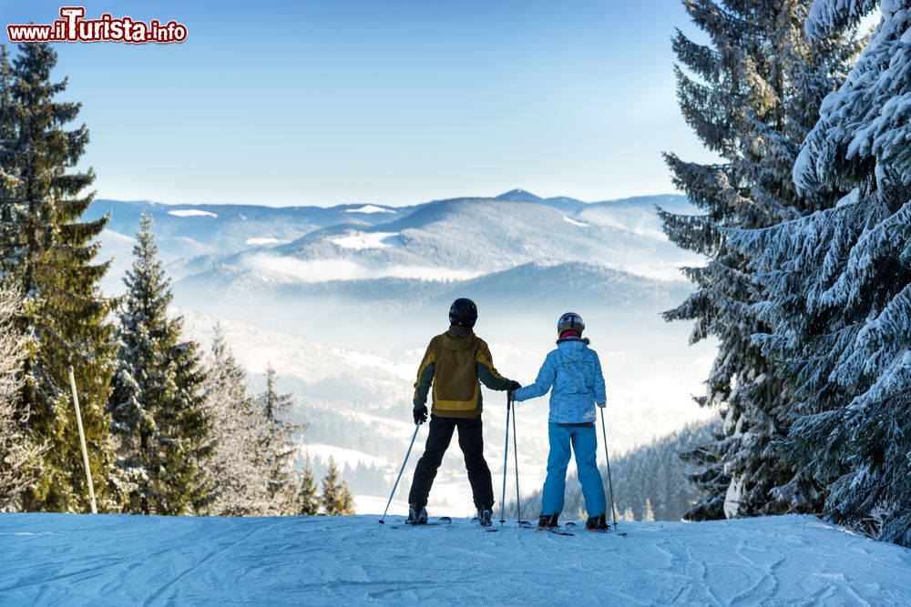 Immagine Un uomo e una donna sugli sci si tengono per mano su una pista innevata di Bukovel, Ucraina.