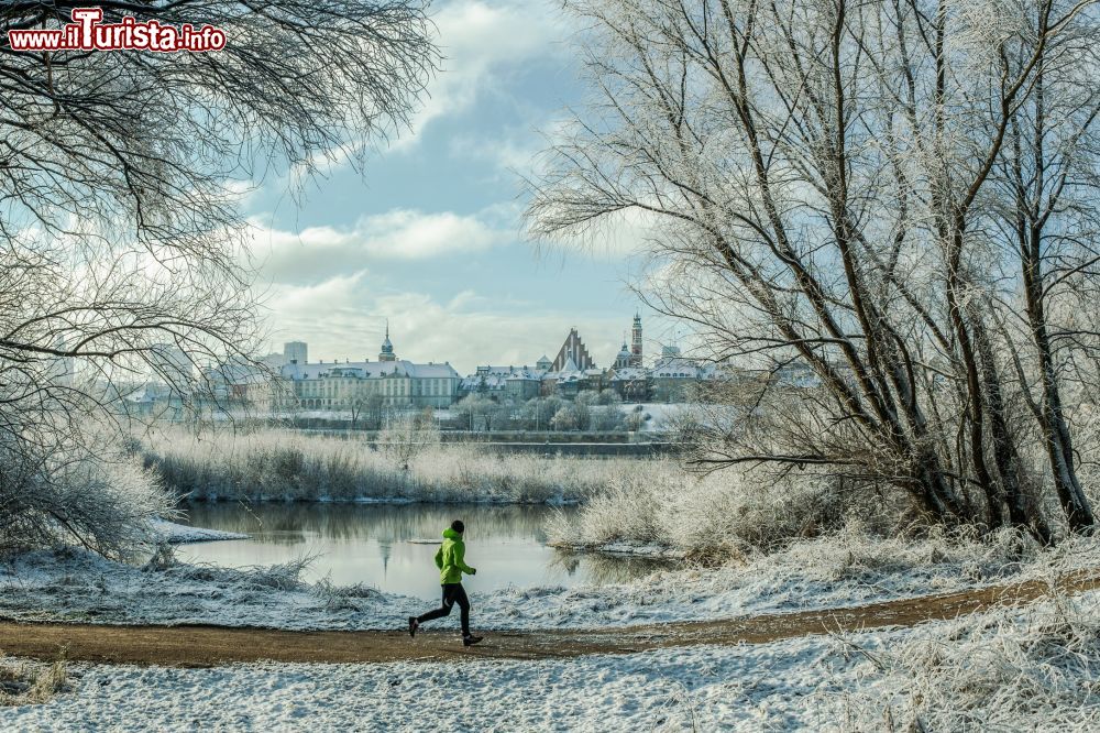 Immagine Un uomo fa jogging in un parco innevato di Varsavia, Polonia. Sullo sfondo, la skyline della capitale.