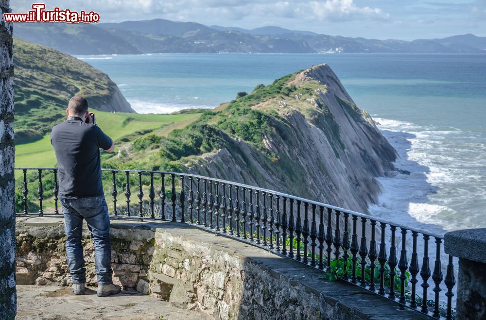 Immagine Un uomo fotografa la costa basca da un punto panoramico di Zumaia, Spagna.
