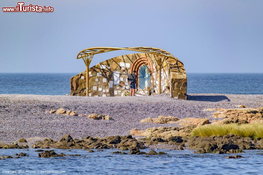 Immagine Un uomo osserva un piccolo monumento religioso sulla spiaggia di Punta del Este, Uruguay - © DFLC Prints / Shutterstock.com