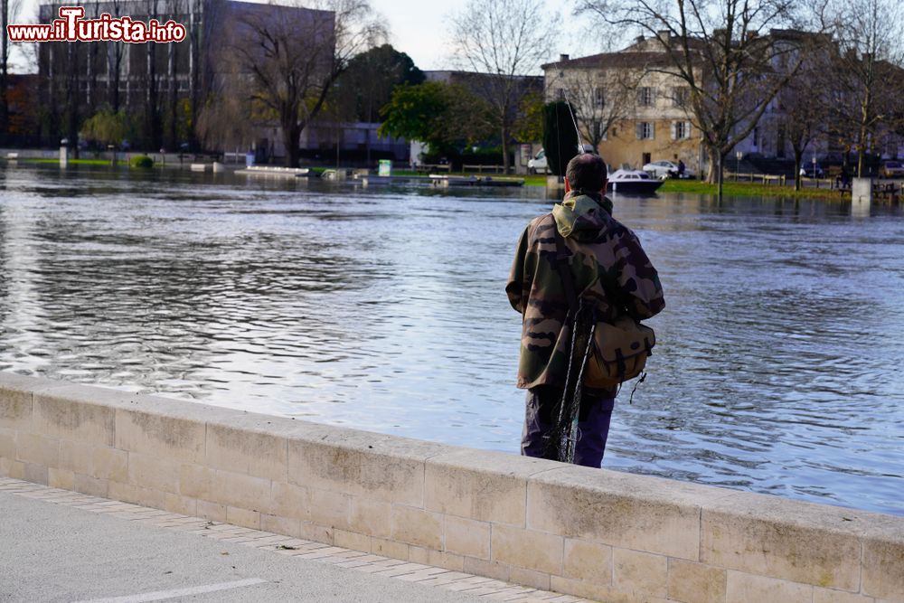 Immagine Un uomo pesca sul fiume Charente nella città di Cognac, Francia.