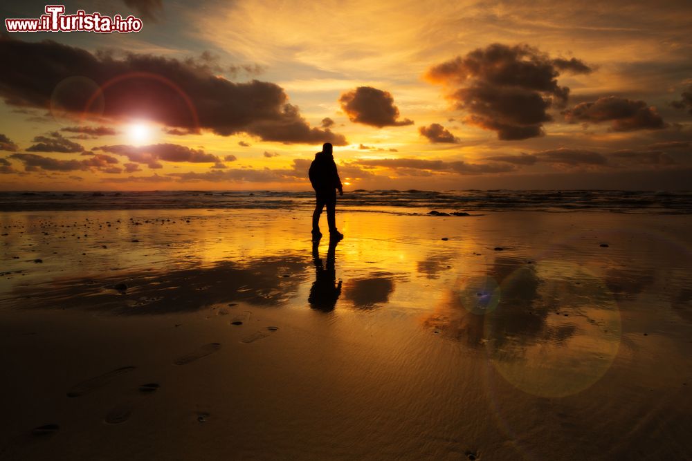 Immagine Un uomo sulla spiaggia con un suggestivo tramonto a Esposende, Portogallo.