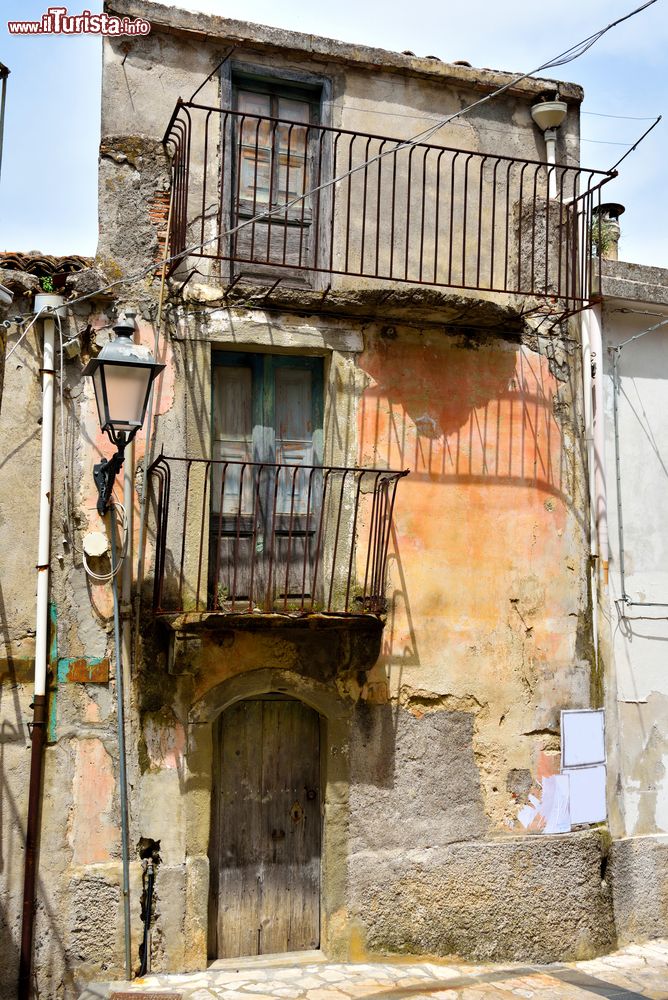 Immagine Un vecchio edificio del borgo di Motta Camastra, Sicilia, con i balconi in ferro.