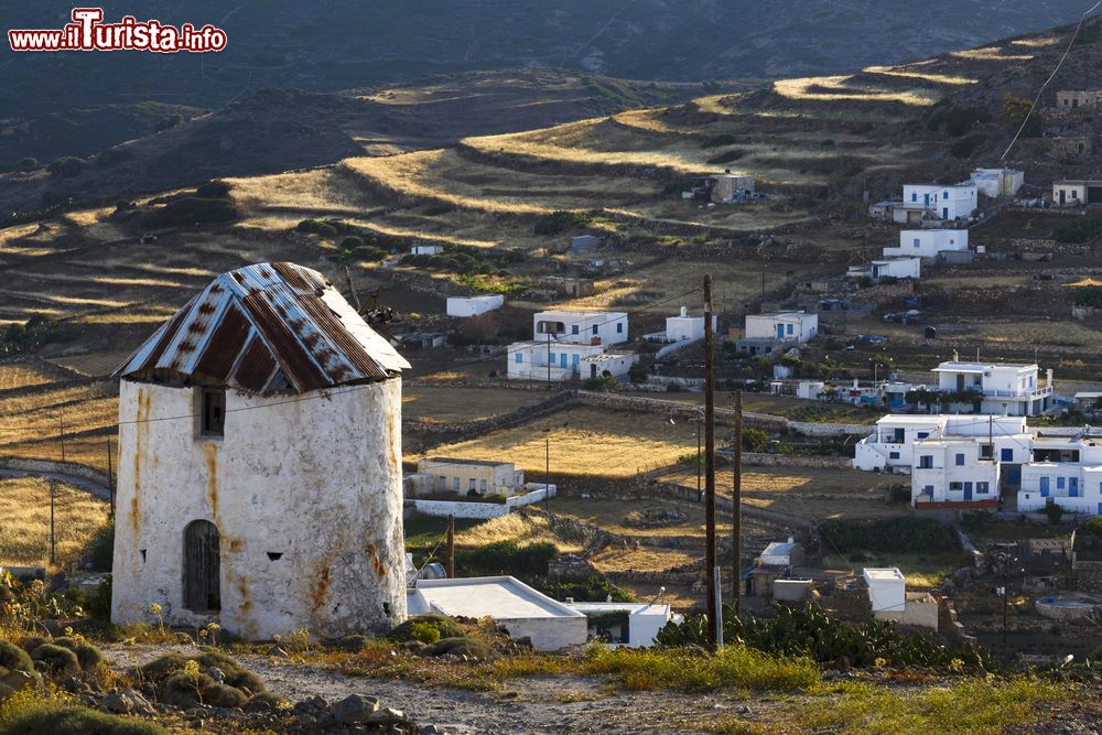 Immagine Un vecchio mulino a vento con la Chora sullo sfondo, isola di Kimolos (Grecia).