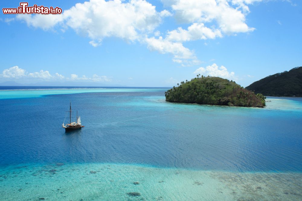 Immagine Un veliero ormeggiato al largo dell'isola di Huahine, sud Pacifico, Polinesia Francese. L'acqua assume le tonalità del blu e dell'azzurro.