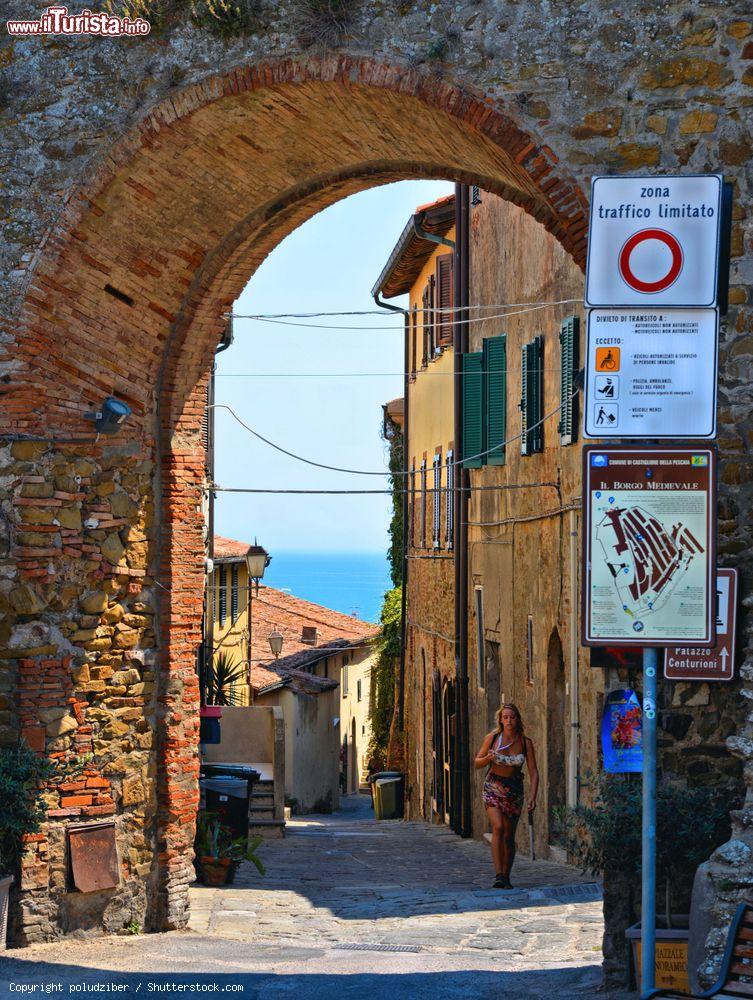 Immagine Un vicoletto del centro storico di Castiglione della Pescaia, Toscana. Una delle porte d'ingresso al borgo medievale con il mare sullo sfondo - © poludziber / Shutterstock.com