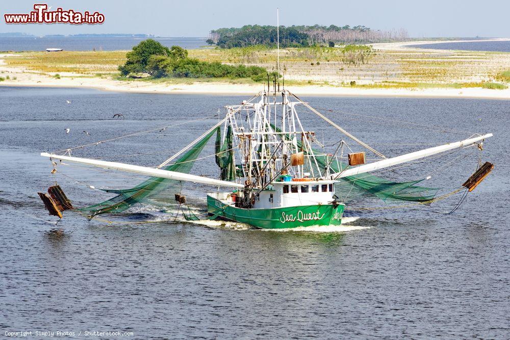 Immagine Una barca da pesca attraversa il canale della baia di Biloxi con le reti stese, Mississipi, Stati Uniti. L'industria della pesca è una delle principali attività economiche della città - © Simply Photos / Shutterstock.com