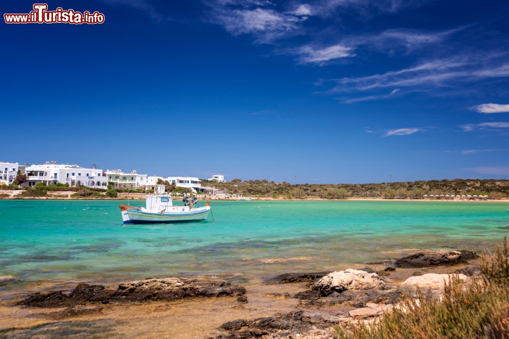 Immagine Una barca da pesca ormeggiata davanti al litorale dell'isola di Antiparos, Grecia. Sullo sfondo, la tradizionale architettura greca.