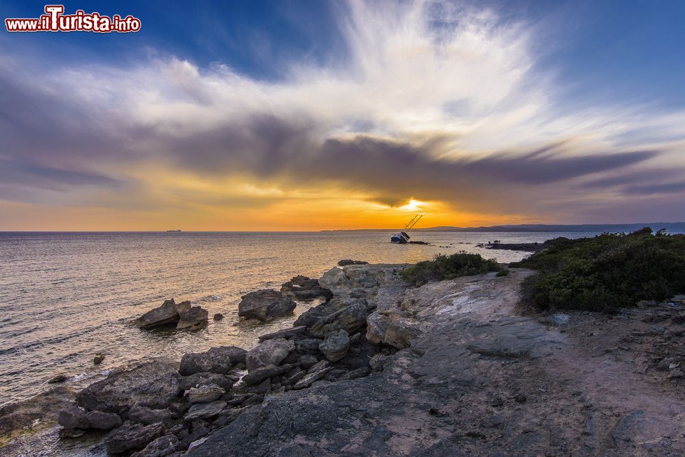 Immagine Una barca naufragata davanti alla costa di Calasetta (Sardegna) con il tramonto.