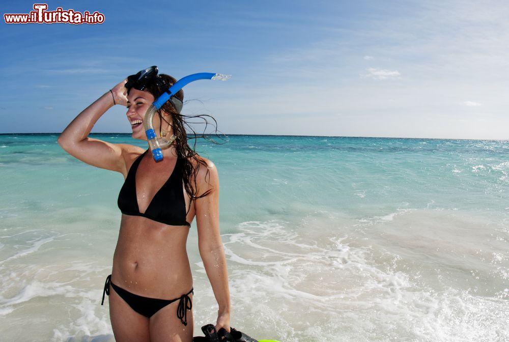 Immagine Una bella ragazza sorride su una spiaggia dopo aver fatto snorkeling a Acklins Island, Bahamas. Acklins, che è anche un distretto dell'arcipelago delle Bahamas, si trova in una larga laguna nota come Bight of Acklins.