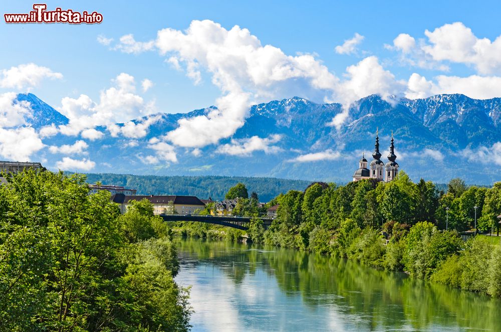 Immagine Una bella veduta delle Alpi fotografate da Villach, Austria. Sullo sfondo, una chiesetta sulle rive del fiume.