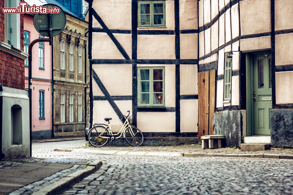 Immagine Una casa a graticcio nel centro di Lund, Svezia, con una bicicletta parcheggiata accanto a una finestra.