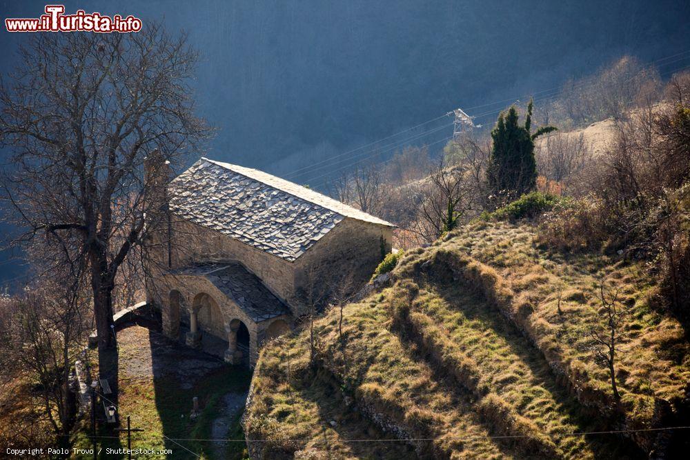 Immagine Una chiesa in pietra immersa nel paesaggio agreste vista dall'alto di Triora, Liguria - © Paolo Trovo / Shutterstock.com