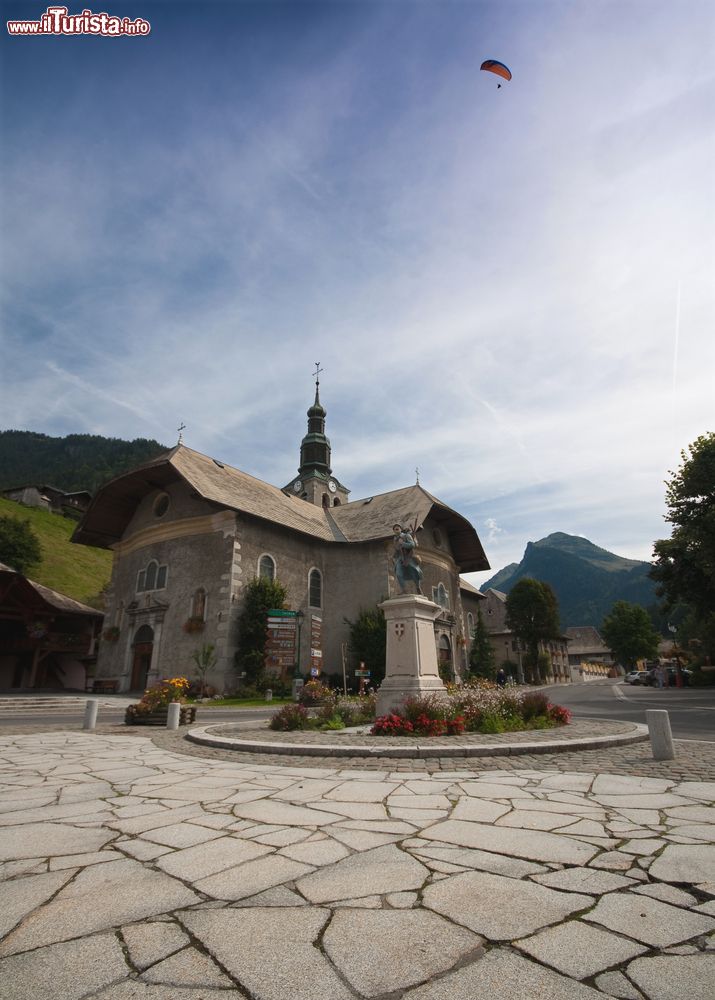 Immagine Una chiesetta nel borgo montano di Morzine, Francia. In primo piano, una piazzetta con statua.