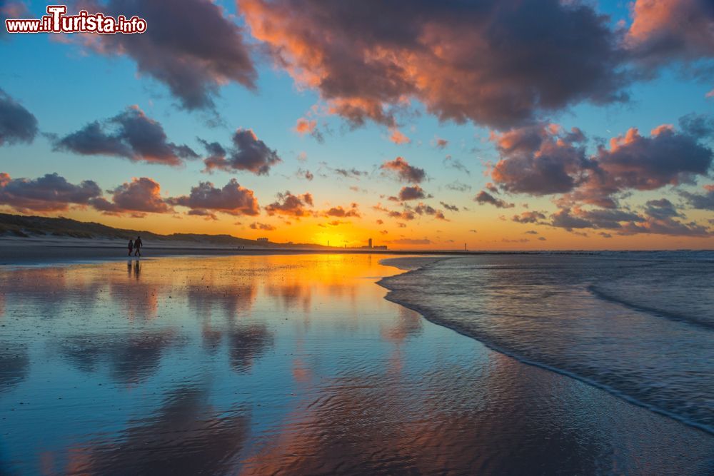 Immagine Una coppia passeggia lungo la spiaggia sabbiosa di Ostenda al tramonto, Belgio.