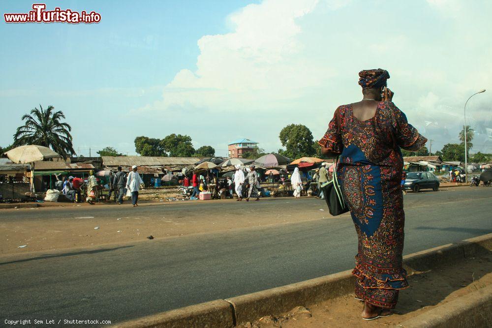 Immagine Una donna africana con un abito tradizionale cammina nella città di Conakry (Guinea) nei pressi di un mercato - © Sem Let / Shutterstock.com