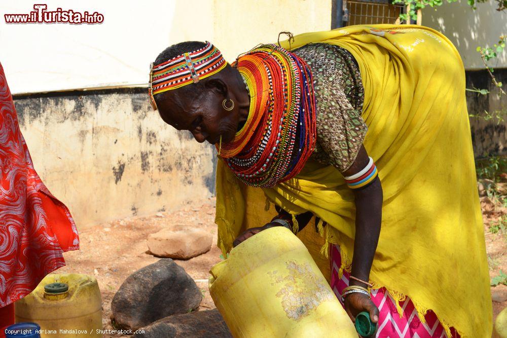 Immagine Una donna in abiti tradizionali raccoglie acqua in un bidone di plastica a Marsabit, Kenya - © Adriana Mahdalova / Shutterstock.com