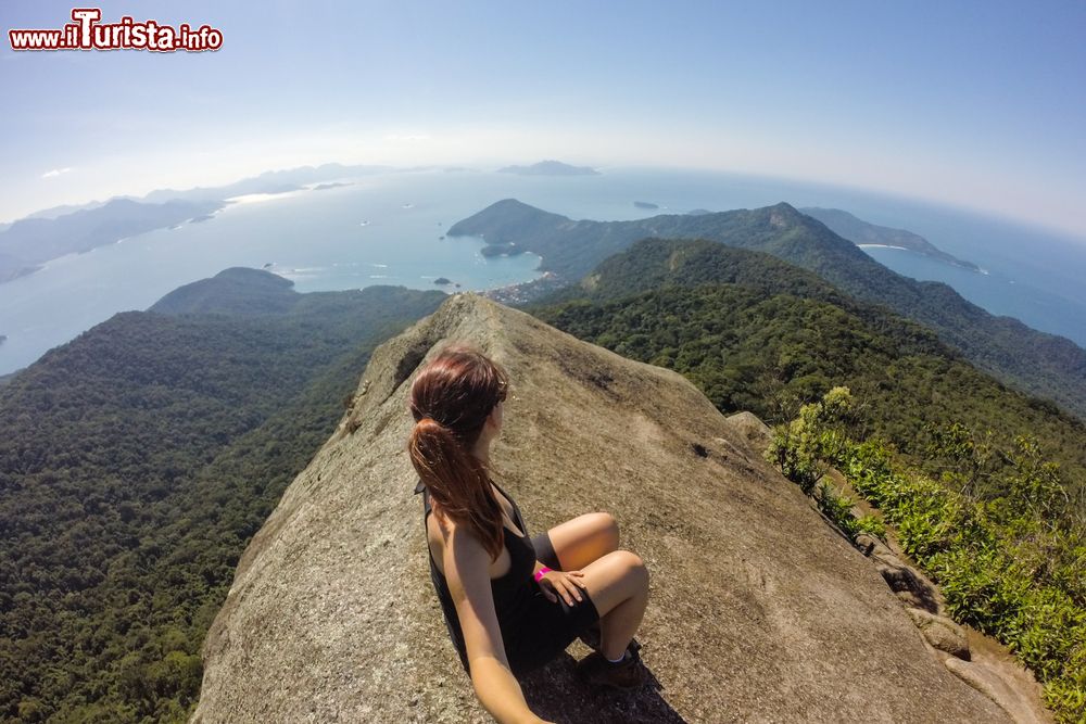 Immagine Una donna seduta sulla cima del Pico do Papagaio a Ilha Grande, Rio de Janeiro, Brasile.