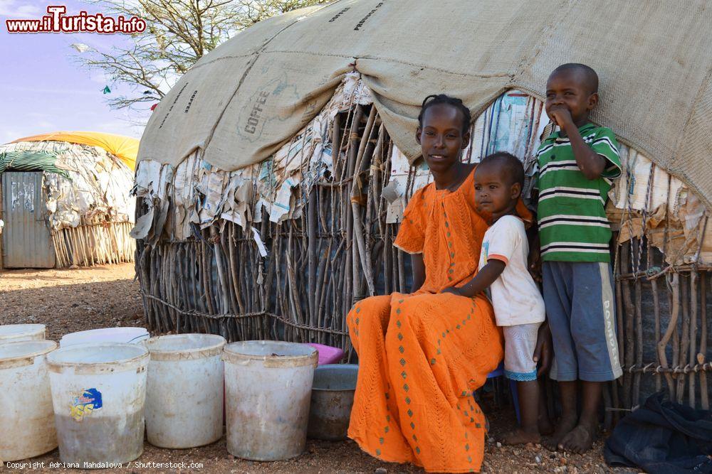 Immagine Una giovane donna keniota lava abiti di fronte alla sua casa di Marsabit in compagnia dei figli - © Adriana Mahdalova / Shutterstock.com