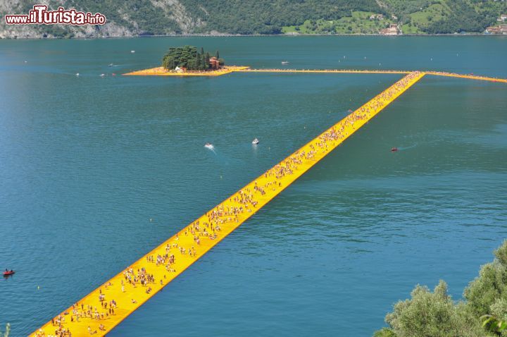 Immagine Una grande folla cammina da Monte Isola fino all'Isola di San Paolo, Lago d'Iseo. La fotografia è scattata dalle alture di Monte Isola - © s74 / Shutterstock.com