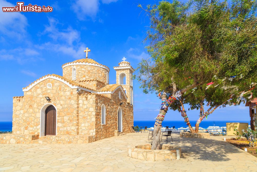 Immagine Una graziosa chiesetta in mattoni sulla collina di Protaras, isola di Cipro. A fare da cornice, l'azzurro del cielo e del mare e il verde della vegetazione.