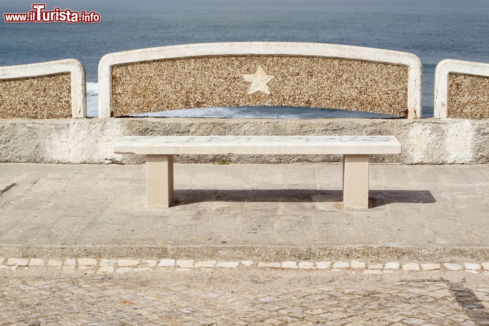 Immagine Una panchina lungo l'oceano a Ericeira, Portogallo. Dalla passeggiata che fiancheggia il litorale è possibile ammirare le acrobazie dei surfisti in azione.