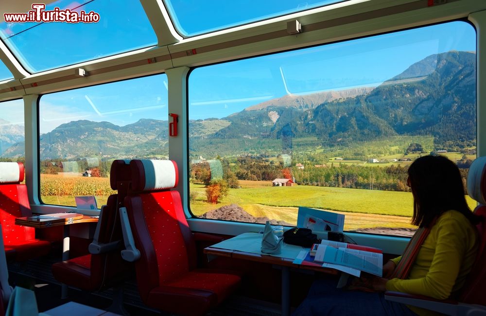 Immagine Una passeggera ammira il panorama estivo della campagna svizzera dal Glacier Express. Dal 2006 questo treno turistico dispone di nuovi vagoni panoramici di prima e seconda classe; una voce narrante in ben sei differenti lingue (francese, tedesco, inglese, giapponese, cinese e italiano) descrive ai viaggiatori le bellezze e le curiosità incontrate lungo il percorso.