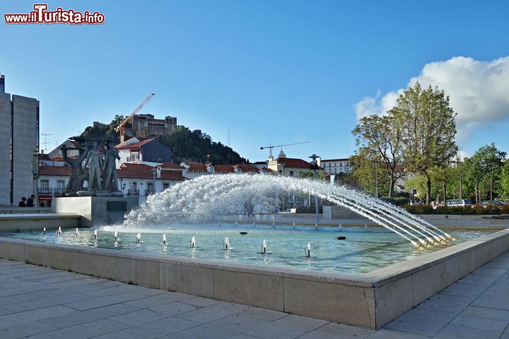 Immagine Una piazza con fontana nel centro della città di Leiria, Portogallo: sullo sfondo, il castello merlato che domina dall'alto di una collina.