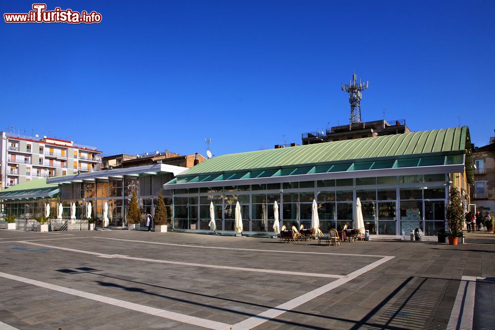 Immagine Una piazza della città di Caserta, Campania, con attività commerciali e gente a passeggio.
