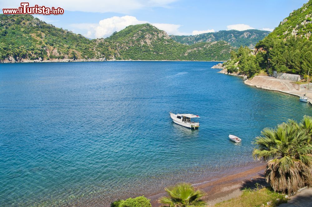 Immagine Una piccola imbarcazione bianca ancorata nel mare vicino a Marmaris, Turchia. Sullo sfondo le montagne turche fotografate in una calda giornata estiva.