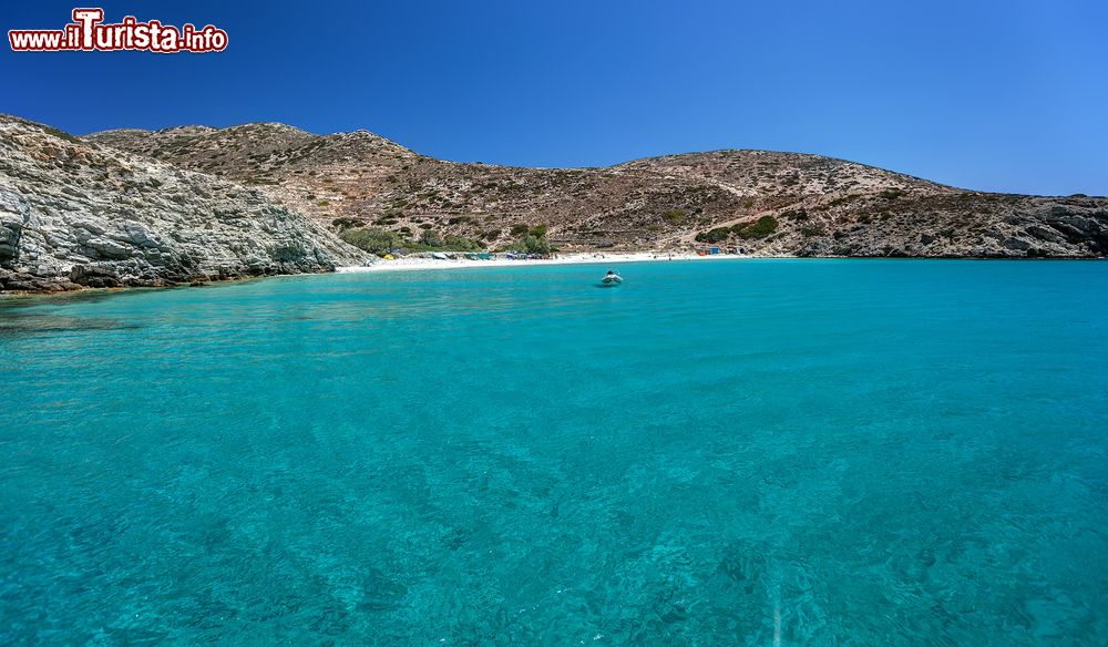 Immagine Una piccola spiaggia di sabbia lambita dalle acque dell'Egeo, isola di Donoussa, Grecia. Sullo sfondo una barca ormeggiata.