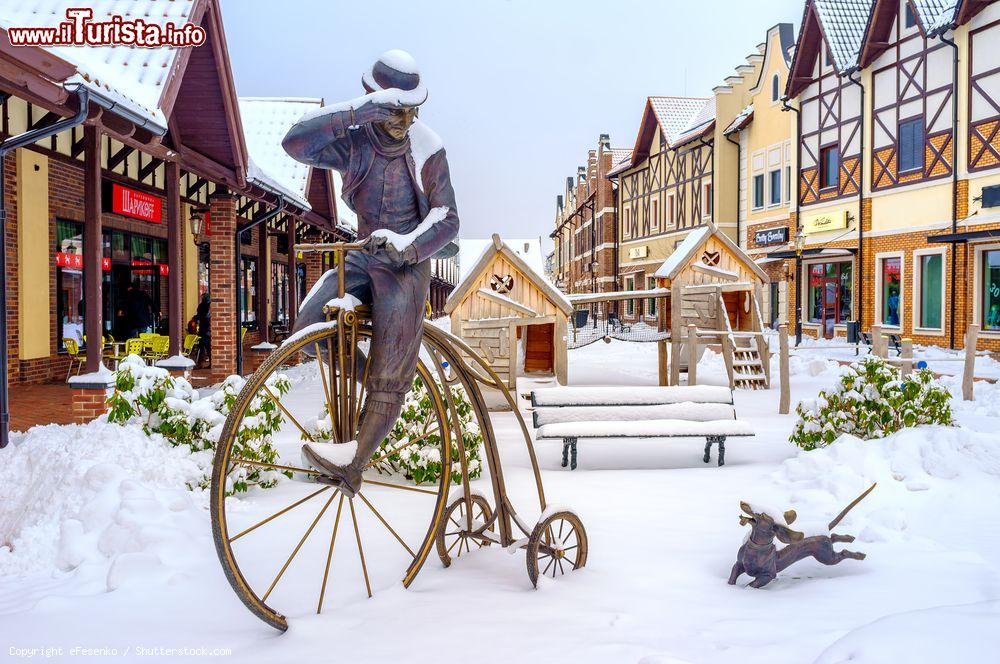 Immagine Una simpatica statua nell'area commerciale olandese di Kiev, Ucraina. La scultura in bronzo di un bassotto corre accanto a un uomo in bicicletta - © eFesenko / Shutterstock.com