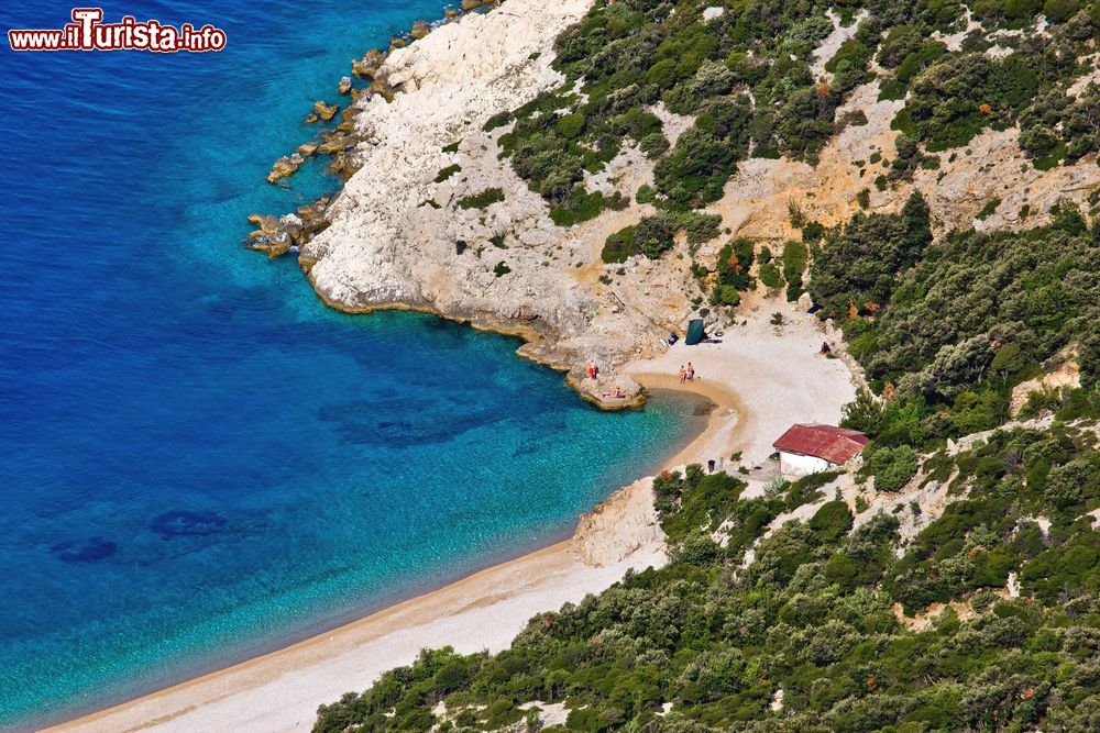 Immagine Una spiaggia di Lubenice sull'isola di Cres, Croazia. Il bianco della sabbia contrasta le sfumature blu del mare e il verde della vegetazione lussureggiante.