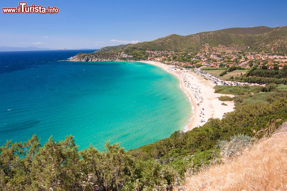 Immagine Una spiaggia di Solanas con sabbia bianca, colline con vegetazione, mare blu e il piccolo villaggio, frazione del Comune di Sinnai, Sardegna.