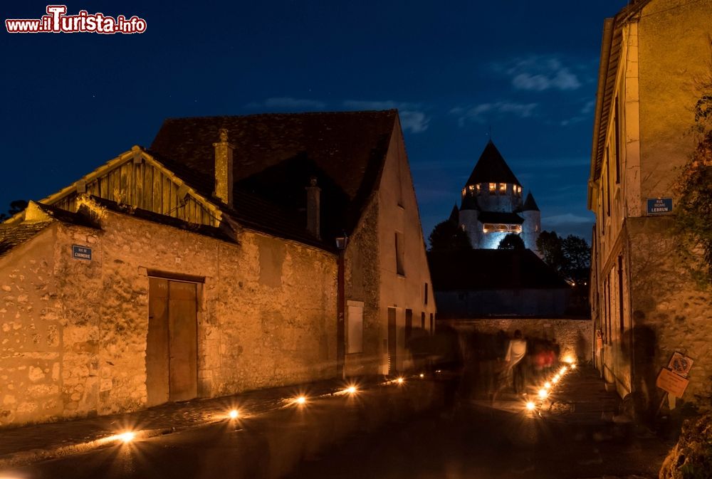 Immagine Una splendida veduta notturna del castello di Provins, Francia, con persone a passeggio.
