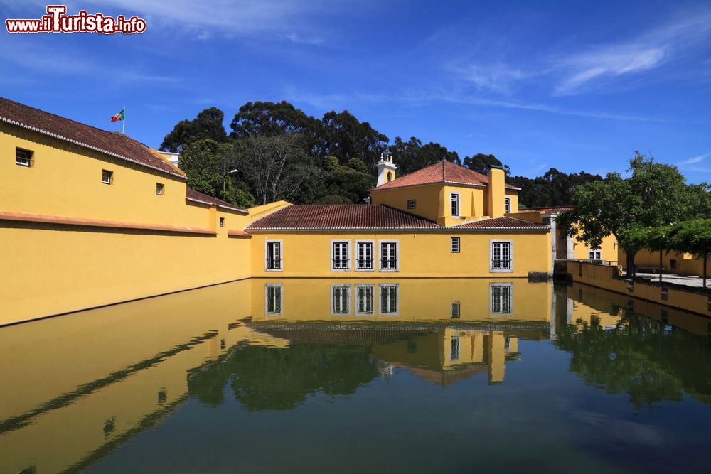 Immagine Una storica fabbrica di polvere da sparo a Oeiras, Portogallo. L'edificio si riflette nello stagno del giardino sotto un cielo con qualche nube.