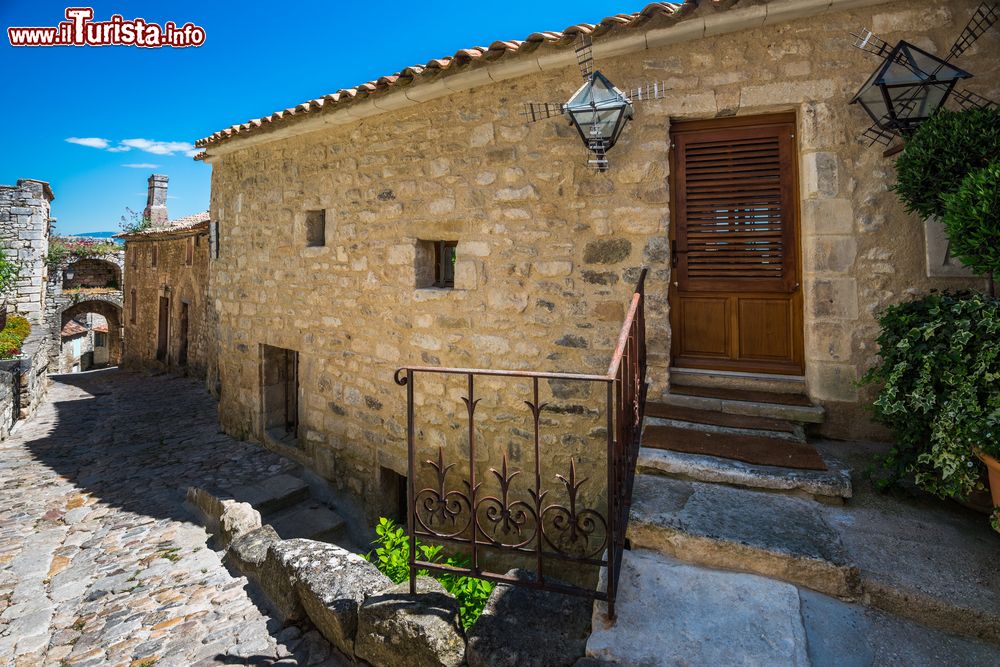 Immagine Una suggestiva casa in pietra con lanterne a forma di mulino a vento in una stradina di Bonnieux, Provenza, Francia.