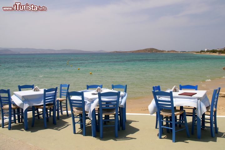 Immagine Taverna greca sul mare a Naxos, Grecia - Tavoli e sedie di un tipico ristorante greco che si affaccia sull'Egeo: nelle trattorie di Naxos, come in tutte quelle della Grecia, si possono assaporare i migliori piatti delle specialità gastronomiche locali ammirando paesaggi incantevoli © kkaplin / Shutterstock.com