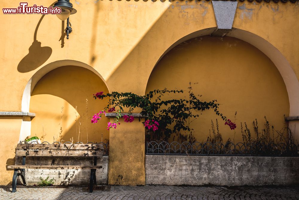 Immagine Una tipica costruzione all'interno di un cortile a Arbus, Sardegna. La facciata color giallo ocra di un vecchio edificio di Arbus con una panchina in legno.
