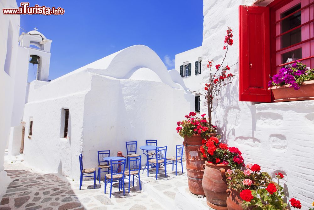 Immagine Una tipica stradina greca sull'isola di Amorgo, Grecia, con tavolini e sedie azzurre.