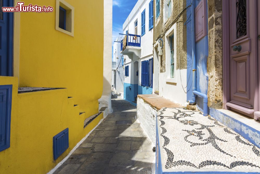 Immagine Una tipica viuzza del villaggio di Mandraki a Nisyros, Grecia. Le case che si affacciano sul centro storico sono caratterizzate da dettagli dipinti con colori pastello.