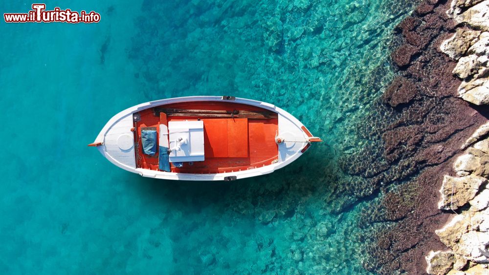 Immagine Una tradizionale barchetta da pesca nel porto di Schinoussa (Cicladi) con l'acqua azzurra e cristallina, Grecia.