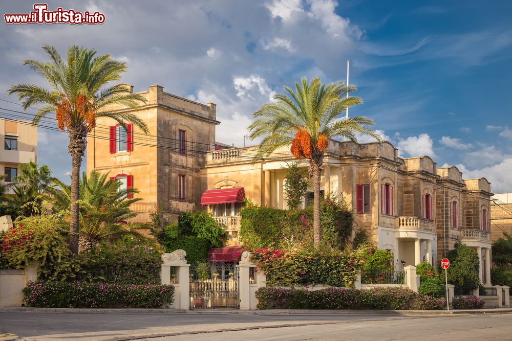 Immagine Una tradizionale casa con palme a Sliema, fotografata con qualche nuvola nel cielo blu, Malta.