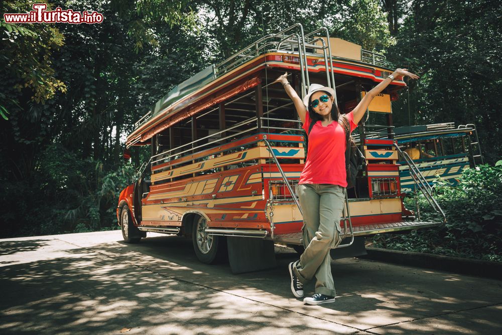 Immagine Una viaggiatrice con zaino in spalla vicino a un bus locale a Ranong, Thailandia.