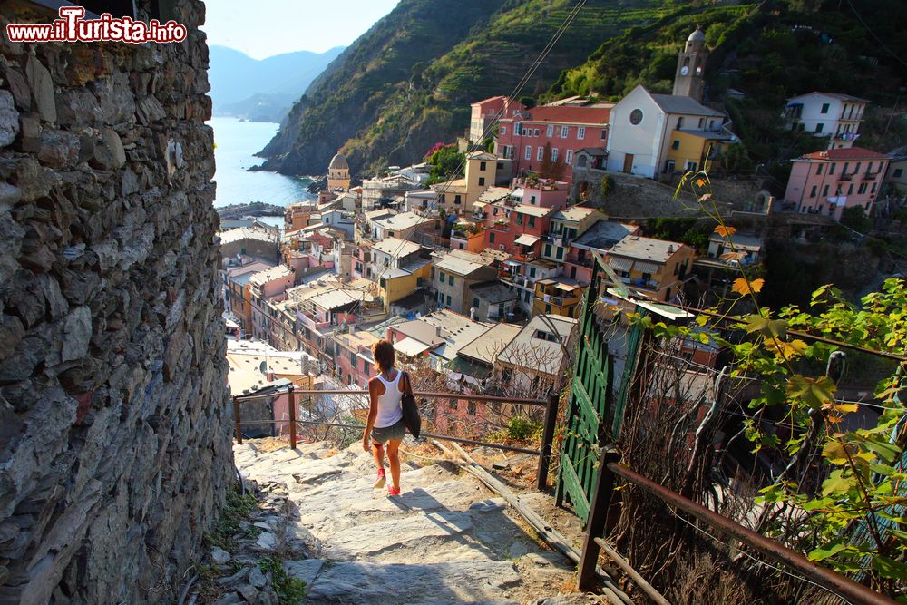 Immagine Una giovane donna scende le scale di una viuzza di Vernazza, La Spezia, Liguria. Percorsi ripidi accompagnano alla piazzetta situata in fondo al porticciolo.