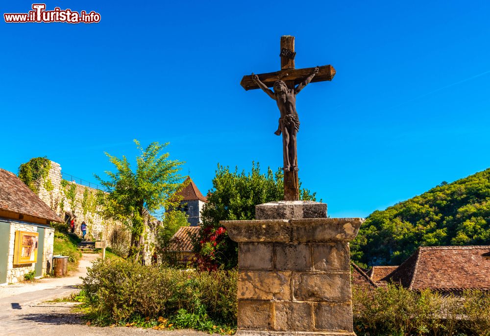 Immagine Uno scorcio del borgo francese di Saint-Cirq-Lapopie in Occitania. Una suggestiva croce con Gesù scolpito nella piazzetta del villaggio medievale.
