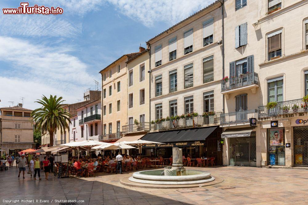 Immagine Uno scorcio del centro di Nimes con ristoranti all'aperto e gente a passeggio, Francia. L'emblema della città è il coccodrillo che rappresenta l'Egitto e la palma che simboleggia la vittoria: si possono osservare lungo le strade in statue e monumenti - © Michael R Evans / Shutterstock.com