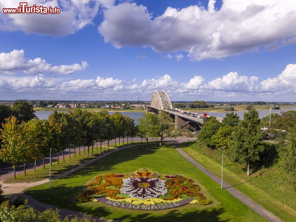 Immagine Uno scorcio del ponte sul fiume Waal nella città di Nijmegen, Olanda. In primo piano lo stemma della città fatto con i fiori in un parco.